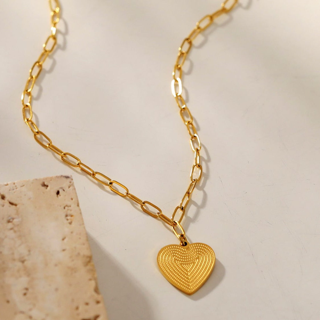 Mini Paper Clip Chain Anchoring a Patterned Heart Charm in Gold
