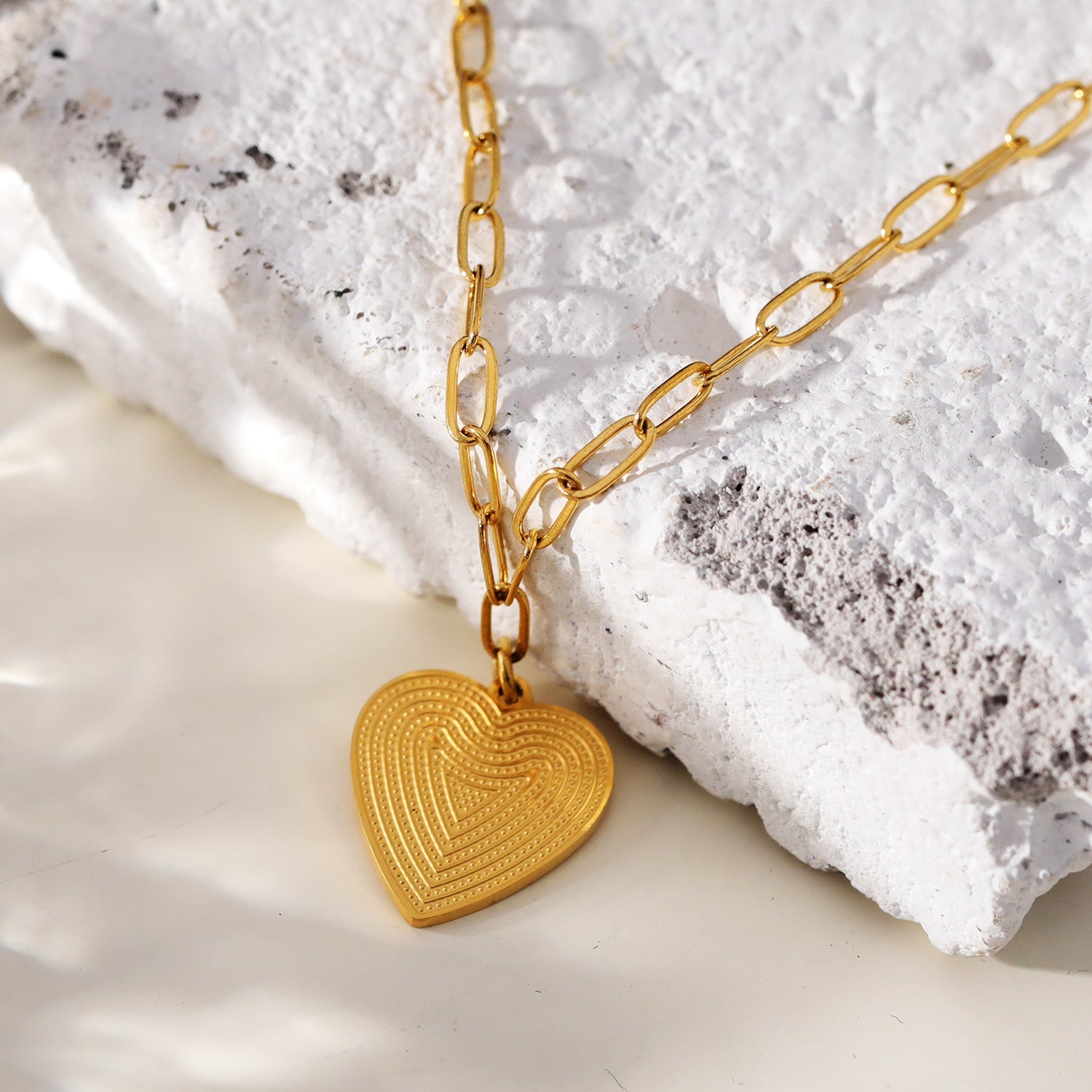 Mini Paper Clip Chain Anchoring a Patterned Heart Charm in Gold